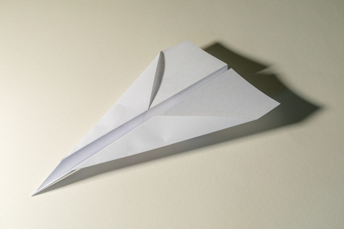 Avion en papier blanc terminé, modèle flèche, posé sur une table