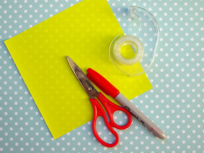 Le matériel pour un marque-page origami : carrés de papier coloré, ciseaux, feutres