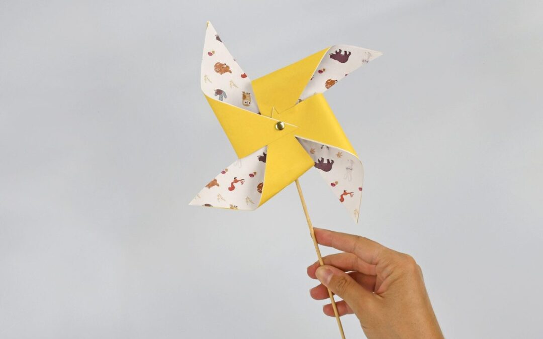 Moulin a vent en papier jaune a motifs animaux tenu au bout d'une tige en bois