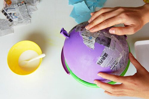 Application de bandes de papier journal encollées sur un ballon de baudruche