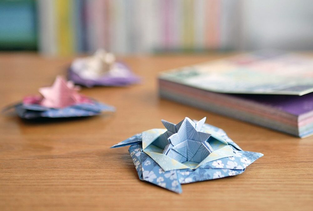 Toupie en papier origami terminee, posee sur une table en bois