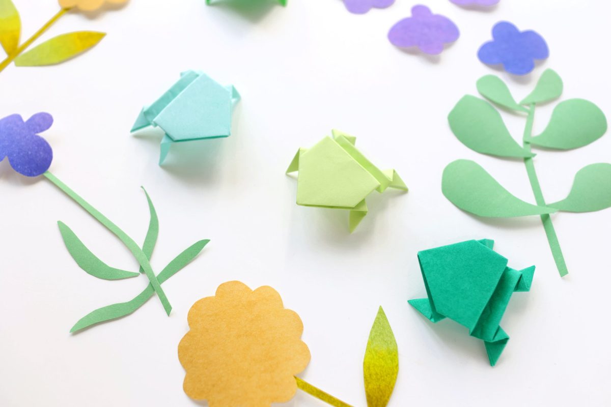Grenouilles en papier vertes et bleues dans un décor de fleurs en papier