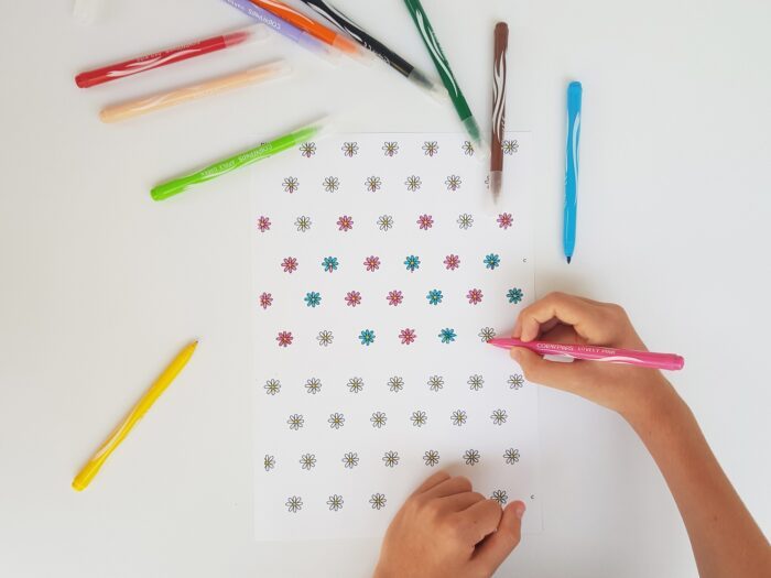 Enfant qui colorie au feutre le carre de papier avant de plier le moulin a vent