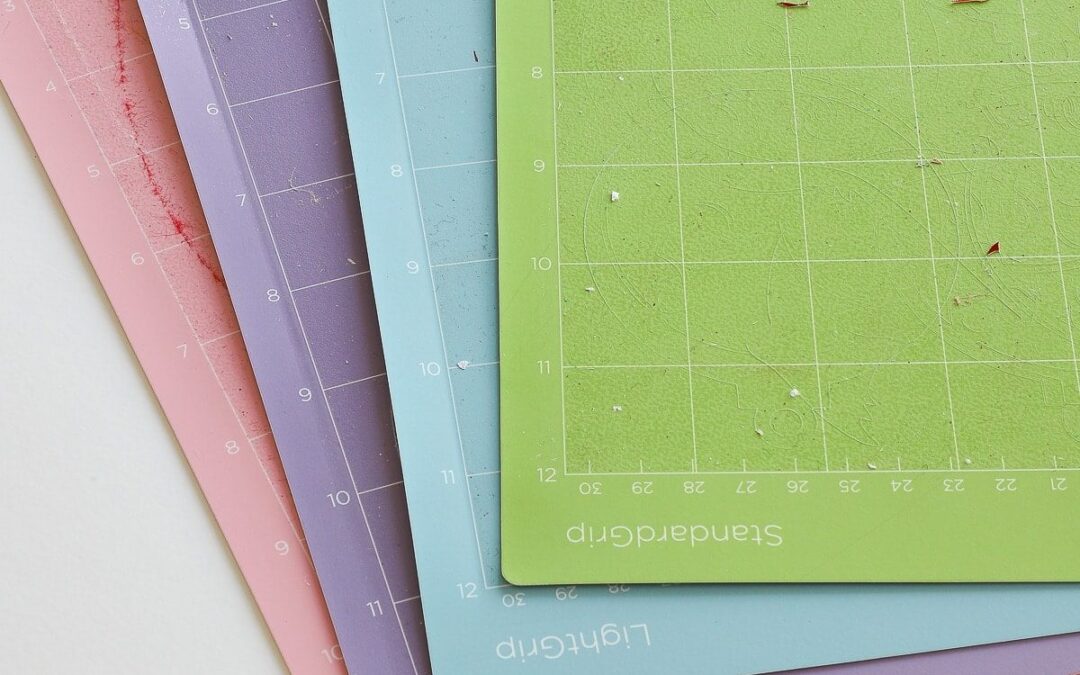Les quatre tapis de découpe Cricut colorés empilés : FabricGrip rose, StrongGrip violet, LightGrip bleu et StandardGrip vert