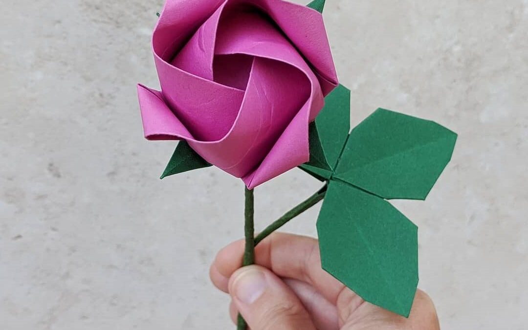 Rose en papier pliée en origami, pétales rose fuchsia avec tige et feuilles en papier vert