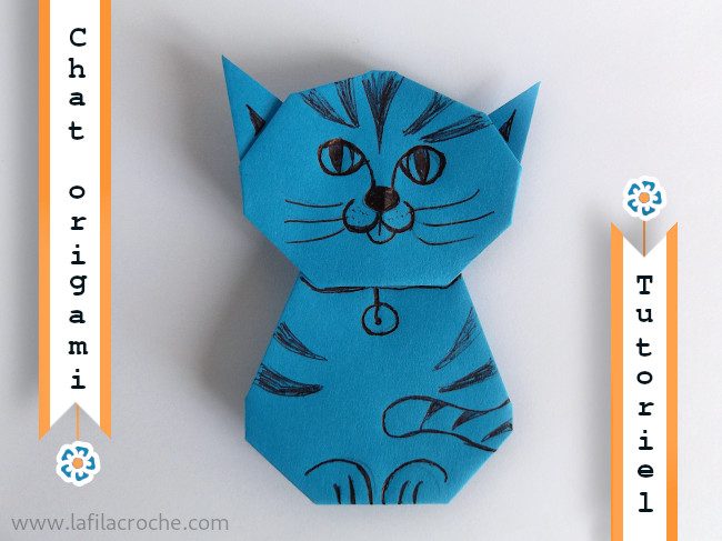 Chat assis en origami bleu au visage et aux rayures dessinés au feutre