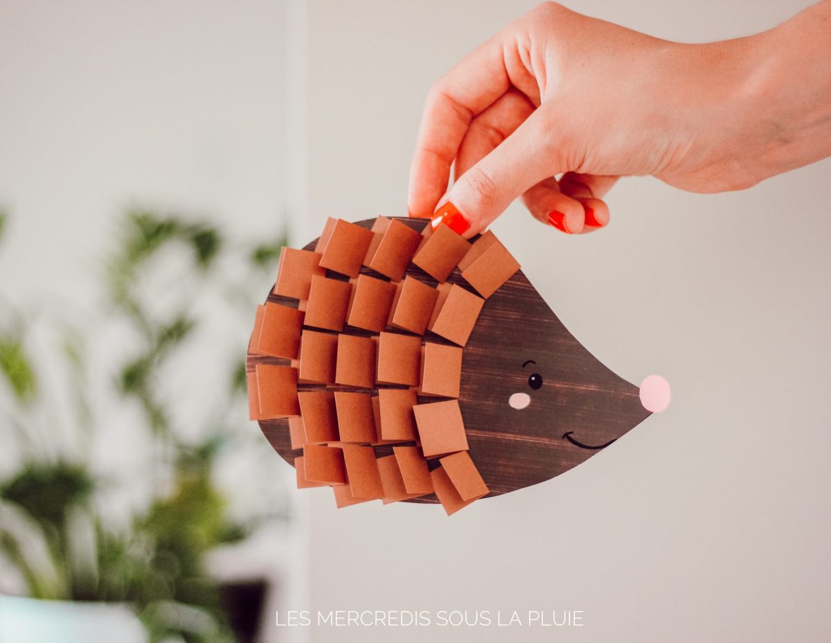 Hérisson en papier tenu à la main, aux piquants faits de petits carrés de papier marron pliés pour un effet de relief