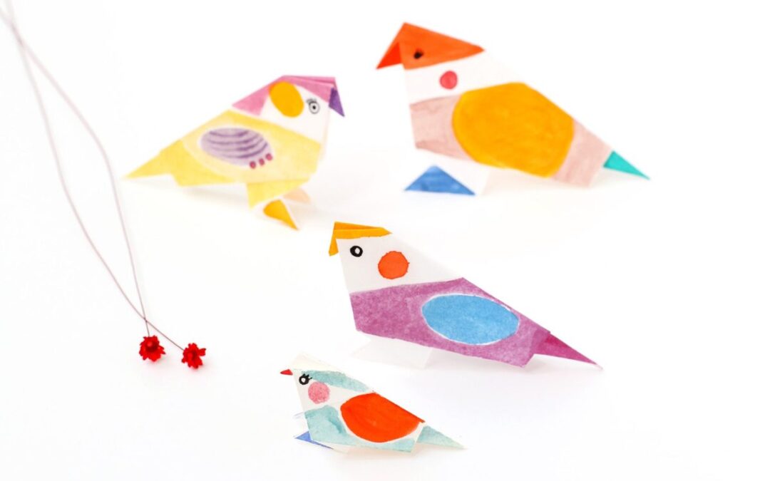 Petits oiseaux en origami en papier coloré, posés sur fond blanc