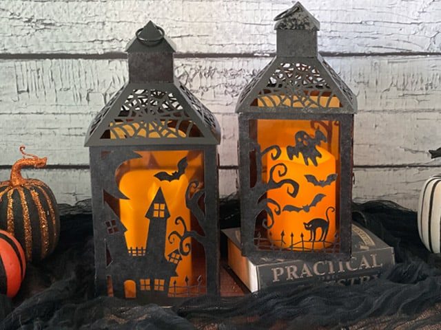 Deux photophores d Halloween en papier decoupe illumines par une bougie LED, motifs maison hantee, fantomes et chat noir