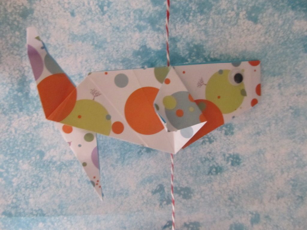 Poisson en origami plié dans du papier à pois, suspendu à une ficelle