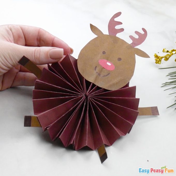 Renne de Noël en rosace de papier plissé bordeaux tenu à la main